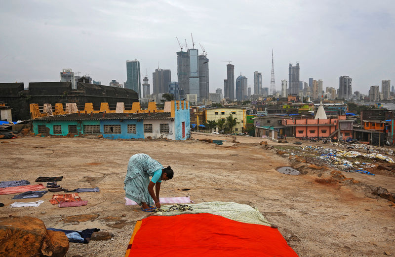 © Reuters. FILE PHOTO: Woman puts clothes to dry overlooking central Mumbai's financial district skyline