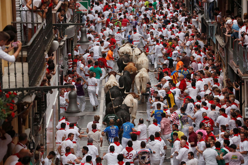 © Reuters. Participantes corriendo delante de toros y novillos durante el primer encierro en el festival de San Fermín en Pamplona