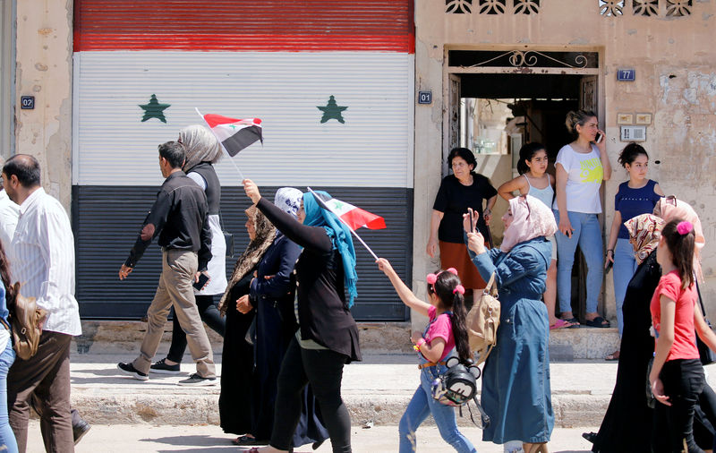 © Reuters. سوريون يعودون إلى مدينتهم القريبة من الحدود اللبنانية في رحلة نظمتها الدولة