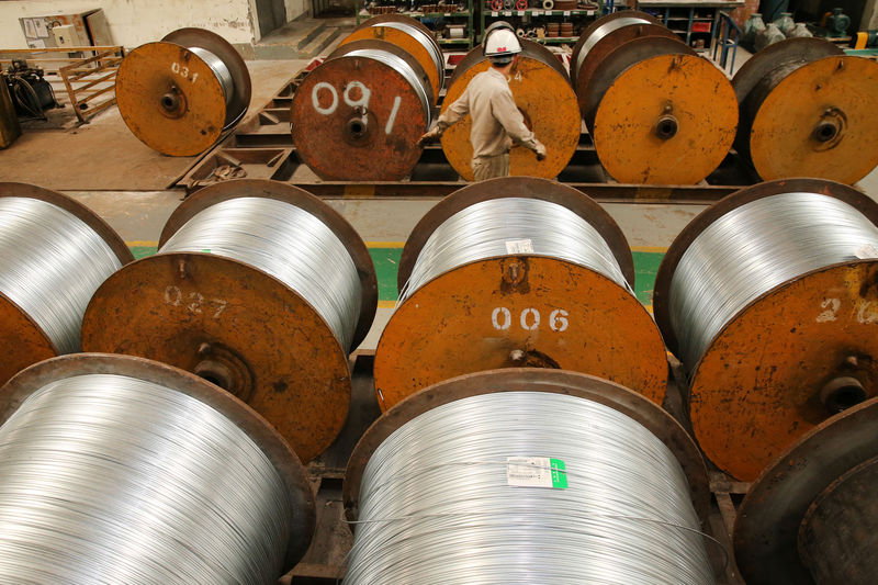 © Reuters. Worker walks past rolls of steel wires at a factory in Nantong, Jiangsu