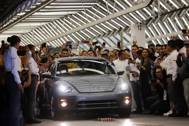 © Reuters. Employees take pictures of a Volkswagen Beetle car during a ceremony marking the end of production of VW Beetle cars, at company's assembly plant in Puebla