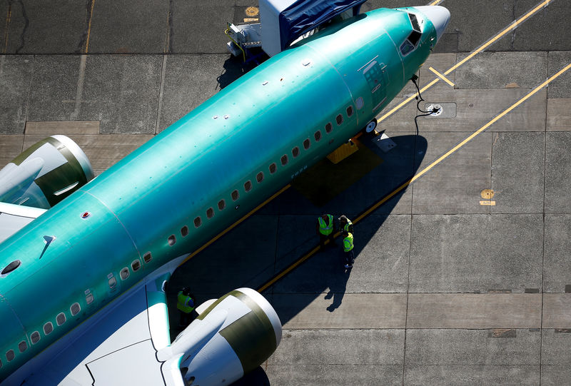 © Reuters. Workers gather next to an unpainted Boeing 737 MAX aircraft seen parked at Renton Municipal Airport near the Boeing Renton facility in Renton