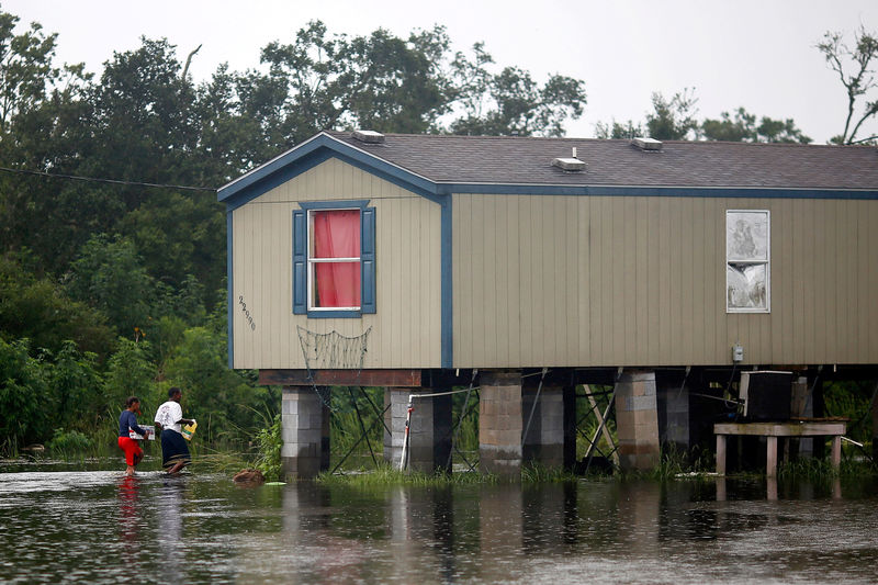 © Reuters. Residents walk through flood water back to their raised house during Hurricane Barry in Plaquemines Parish