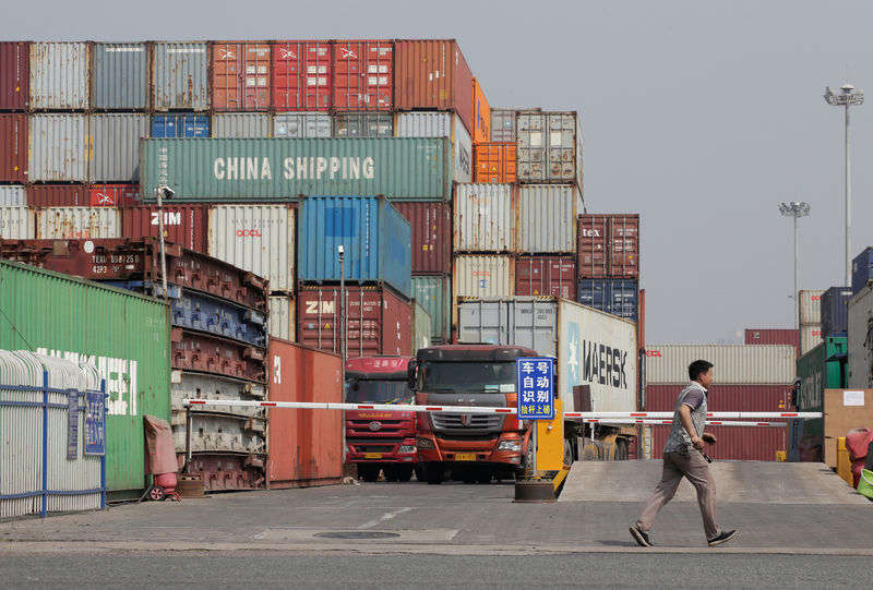 © Reuters. A man walks next to containers in a logistics center near Tianjin Port