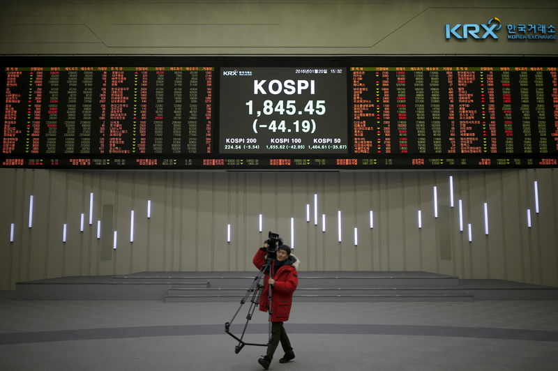 © Reuters. FILE PHOTO:  A journalist walks past electronic board of KOSPI at the Korea Exchange  in Seoul
