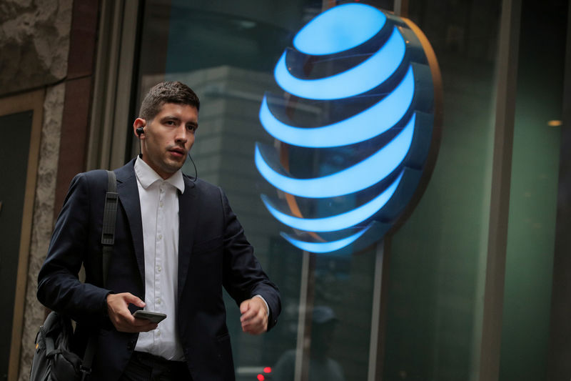 © Reuters. FILE PHOTO: A man uses his phone as he passes by an AT&T store on Wall St. in New York