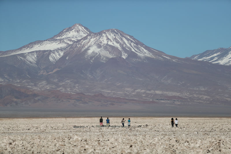 © Reuters. FILE PHOTO: Tourists walk on the Atacama salt flat near Cejar lagoon in the Atacama desert