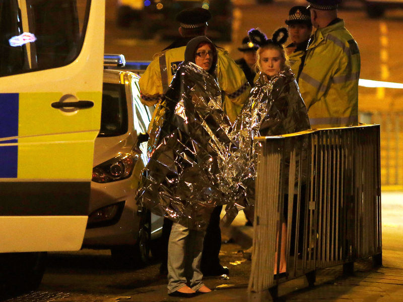 © Reuters. FILE PHOTO: Two women wrapped in thermal blankets stand near the Manchester Arena, where U.S. singer Ariana Grande had been performing, in Manchester, northern England, Britain