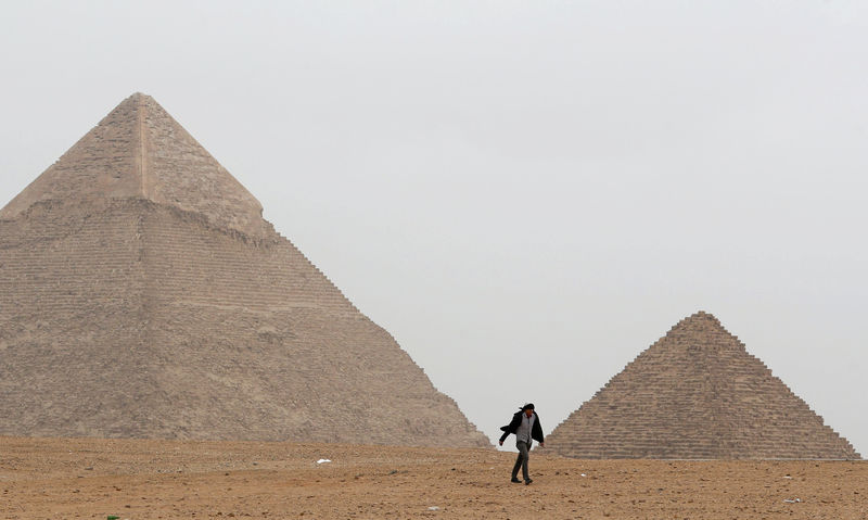 © Reuters. FILE PHOTO: A man walks in front of the Great Pyramids in Giza, on the outskirts of Cairo