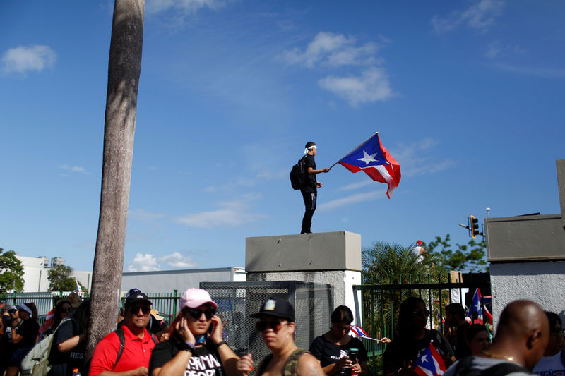© Reuters. A man waves a Puerto Rican flag during ongoing protests calling for the resignation of Governor Ricardo Rossello in San Juan