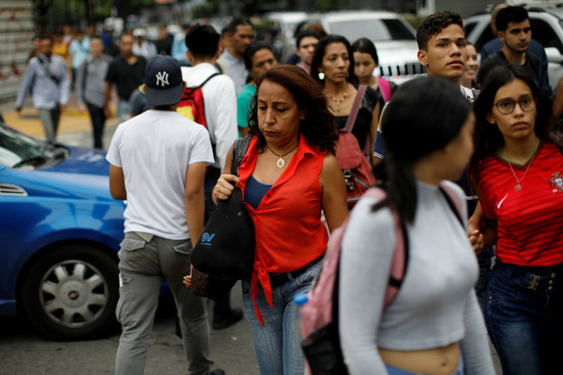 © Reuters. People walk on the street during a blackout in Caracas