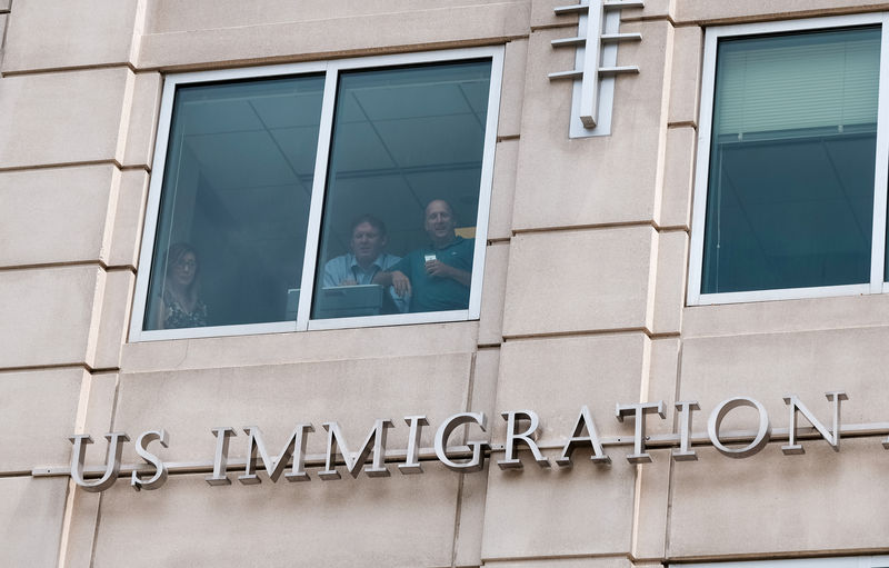 © Reuters. FILE PHOTO:  U.S. Immigration and Customs Enforcement employees watch from a window as activists hold the "Shutdown ICE" rally in Washington