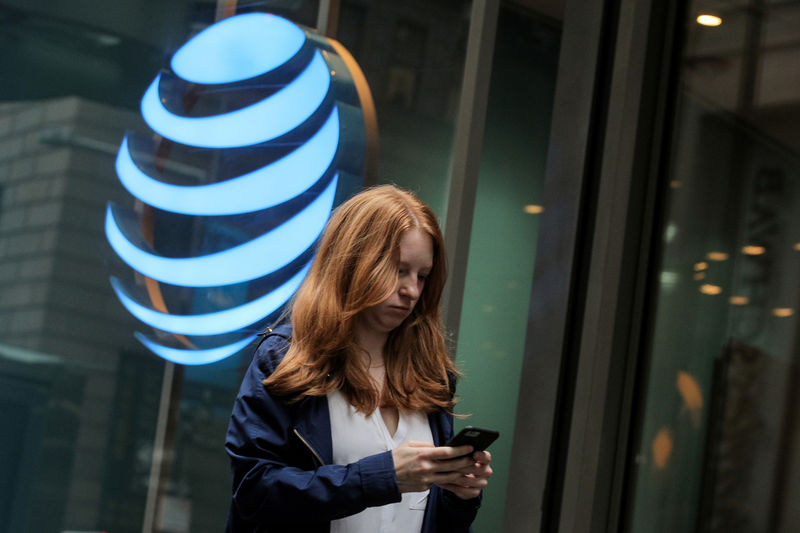 © Reuters. FILE PHOTO: A woman uses her phone as she passes by an AT&T store on Wall St. in New York