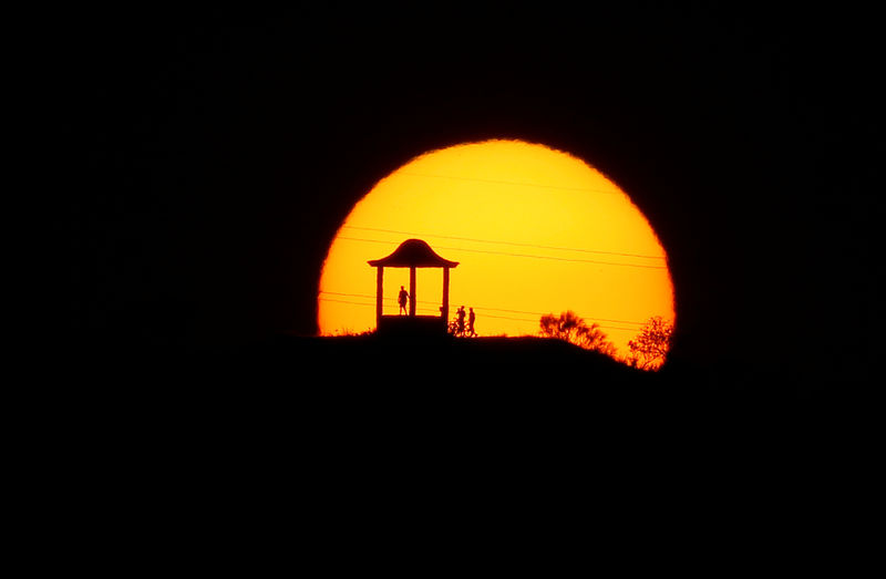 © Reuters. People are silhouetted against the setting sun at "El Mirador de la Alemana" in Malaga