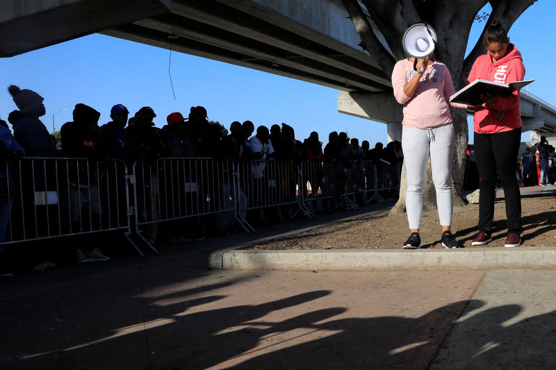 © Reuters. A volunteer shouts numbers on the list for Migrants waiting to apply for asylum in the United States outside the El Chaparral border in Tijuana