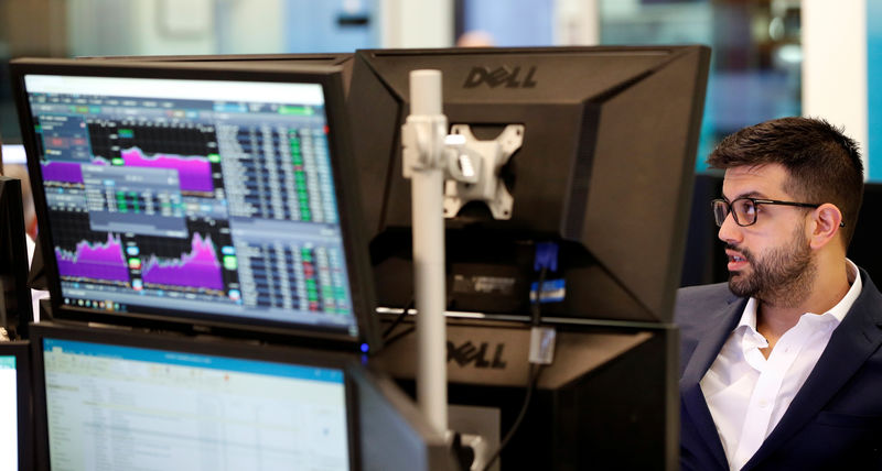 © Reuters. Traders work at their desks whilst screens show market data at CMC Markets in London