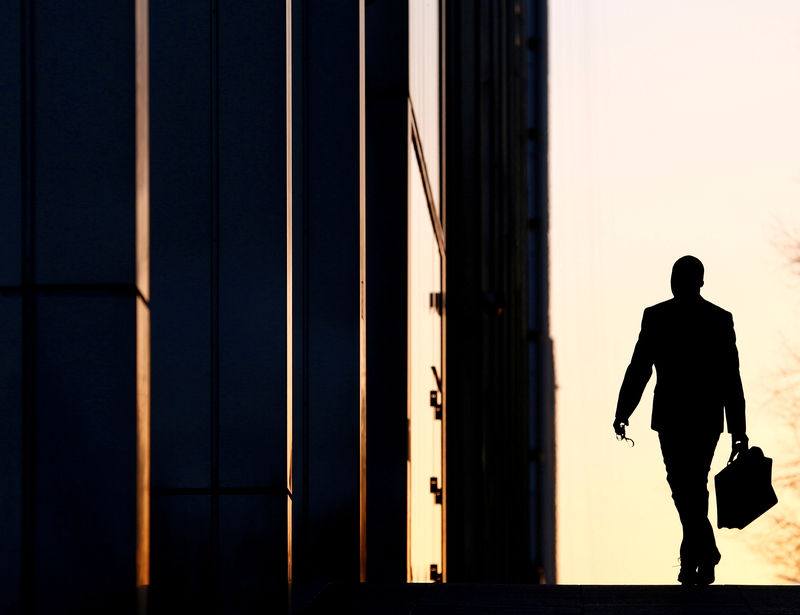 © Reuters. FILE PHOTO - A worker arrives at his office in the Canary Wharf business district in London