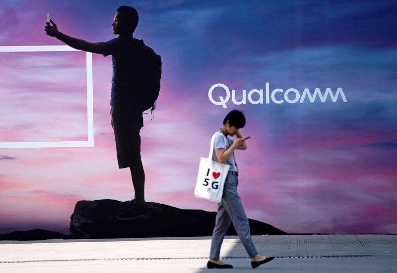 © Reuters. FILE PHOTO: A woman walks past a sign advertising Qualcomm at Mobile World Congress (MWC) in Shanghai