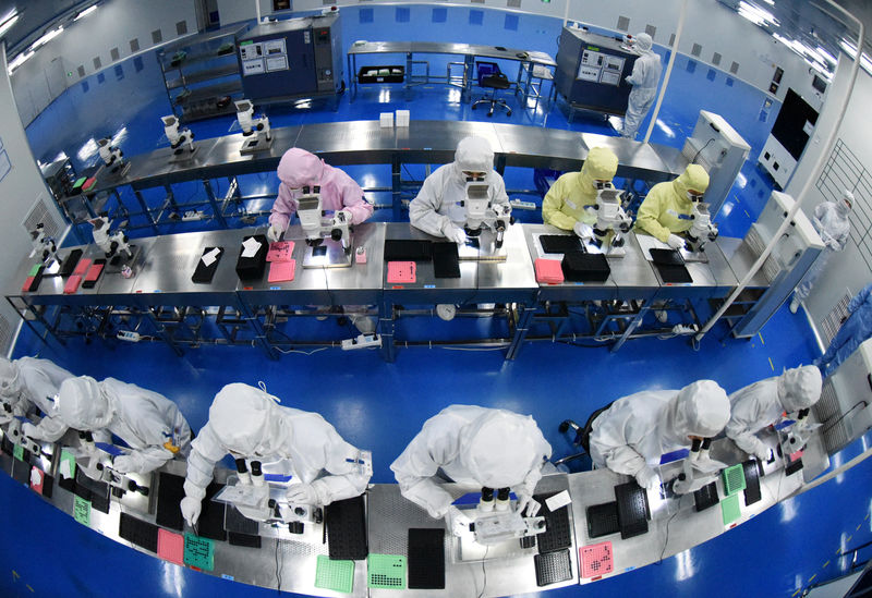 © Reuters. Employees work on a production line manufacturing camera lenses for cellphones at a factory in Lianyungang, Jiangsu