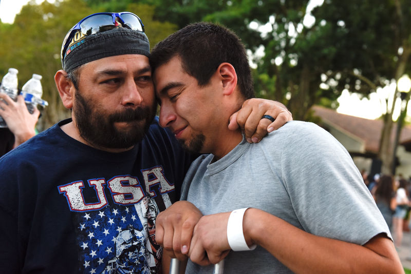 © Reuters. Justin Bates (R), a survivor of the Gilroy Garlic Festival mass shooting, is comforted by his father, Rob Bates, during a vigil outside of Gilroy City Hall