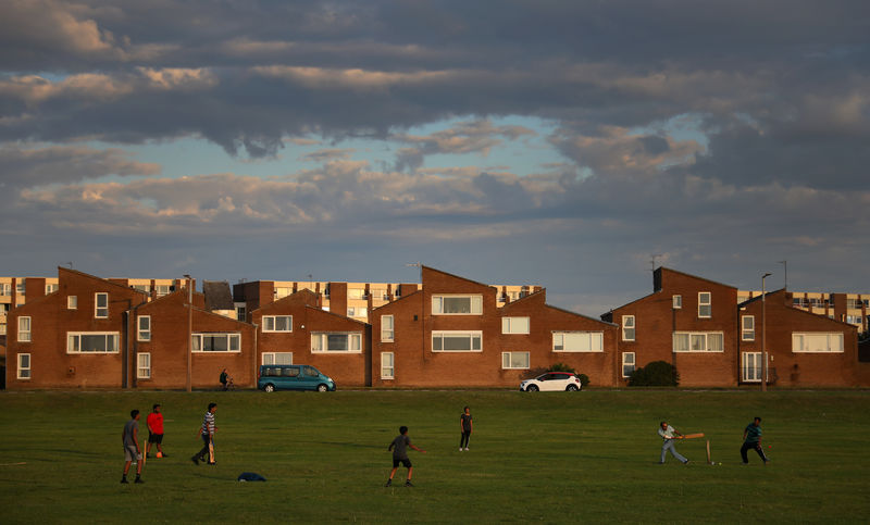 © Reuters. FILE PHOTO: People play cricket in front of houses at sunset in New Brighton