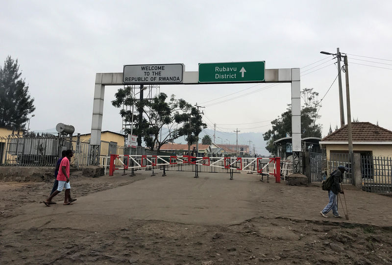 © Reuters. Congolese people walk near the gate barriers at the border crossing point with Rwanda following its closure over Ebola threat in Goma