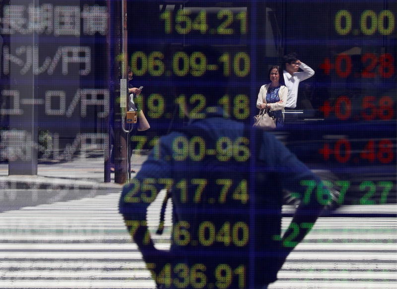 © Reuters. Passersby are reflected on an electronic board showing the exchange rates between the Japanese yen and the U.S. dollar and other market indices outside a brokerage in Tokyo
