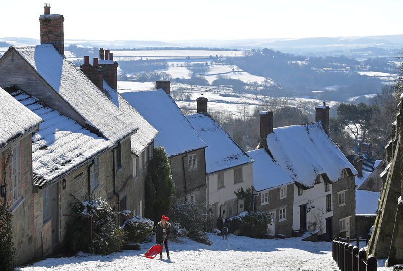© Reuters. FILE PHOTO: People toboggan in the snow on Gold Hill in Shaftesbury, southwest Britain