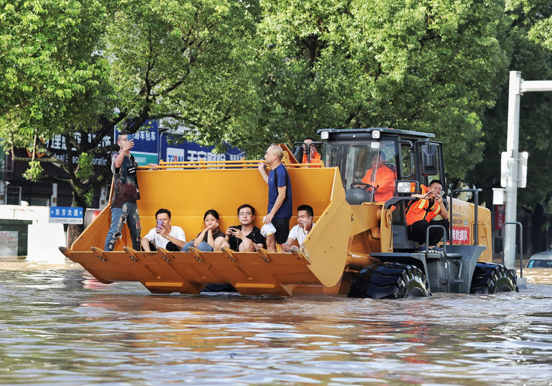 © Reuters. Rescue workers evacuate stranded residents with a bulldozer on a flooded street after typhoon Lekima hit Taizhou, Zhejiang