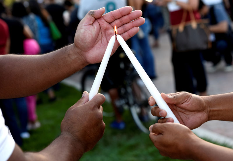 © Reuters. FILE PHOTO: Attendants light candles during a vigil outside of Gilroy City Hall for the victims of a mass shooting at the Gilroy Garlic Festival