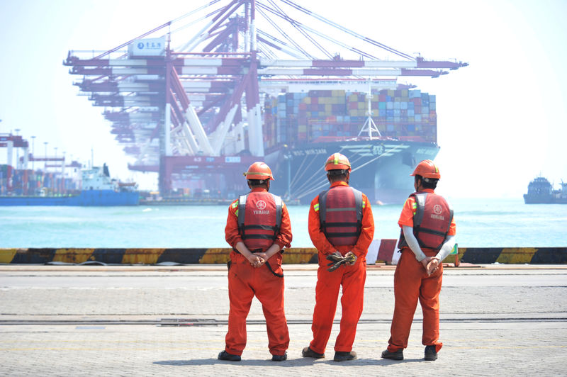 © Reuters. Workers stand at the port of Qingdao, Shandong