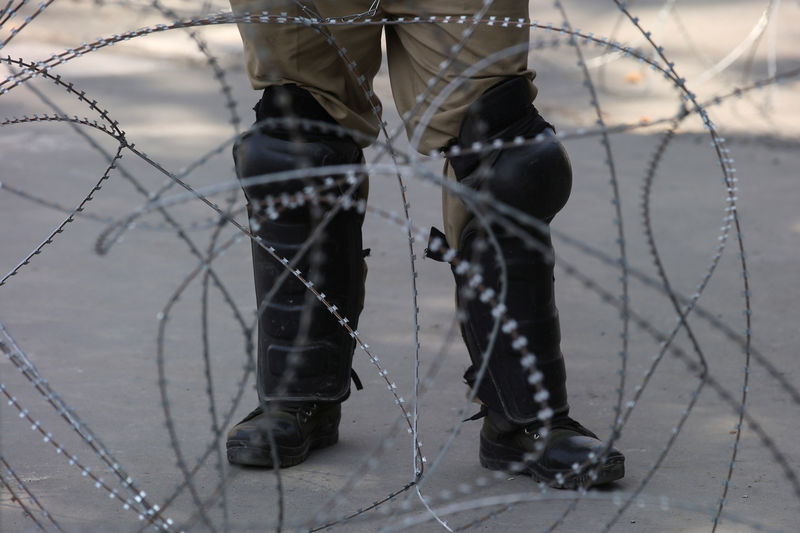 © Reuters. An Indian police officer stands behind the concertina wire during restrictions on Eid-al-Adha after the scrapping of the special constitutional status for Kashmir by the Indian government, in Srinagar