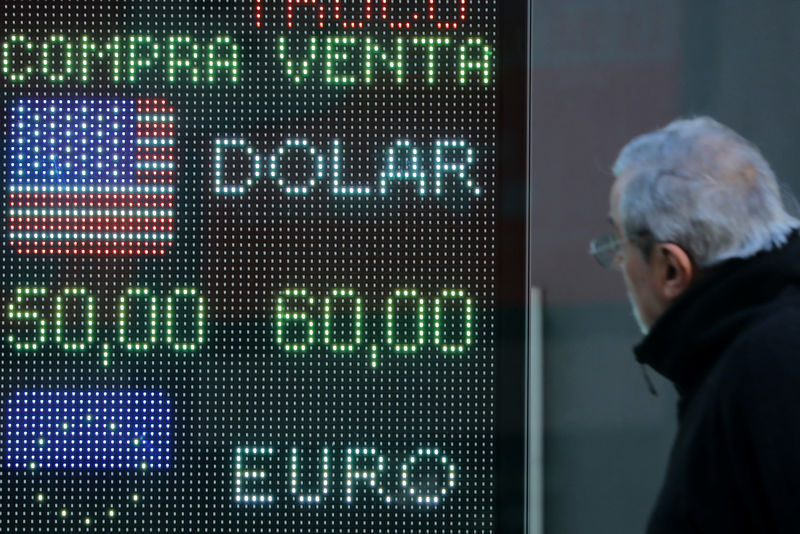 © Reuters. Un hombre mira una pizarra electrónica que muestra los tipos de cambio en el distrito financiero de Buenos Aires.