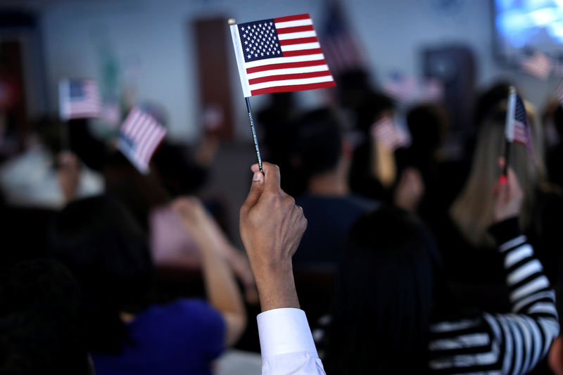 © Reuters. New American citizens wave American flags after taking the Oath of Allegiance during a naturalization ceremony in Newark