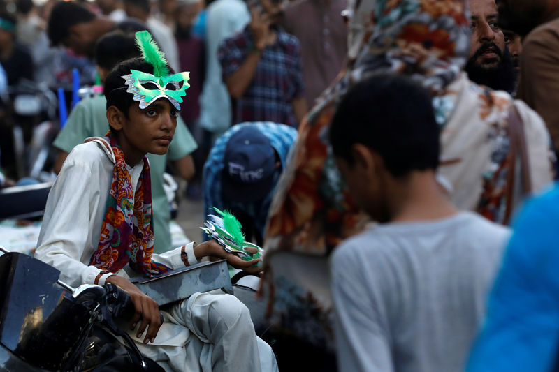 © Reuters. A boy waits for customers as he sells patriotic memorabilia, ahead of Pakistan's Independence Day, along a market in Karachi