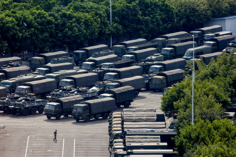 © Reuters. Servicemen walk past military vehicles in the parking area of the Shenzhen Bay Sports Center in Shenzhen across the bay from Hong Kong