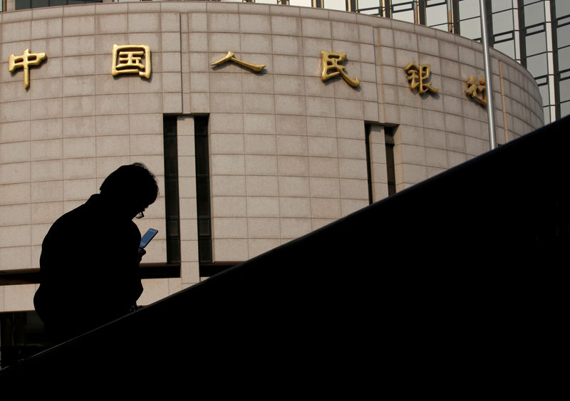 © Reuters. FILE PHOTO: Man sits in front of the headquarters of the People's Bank of China, the central bank, in Beijing