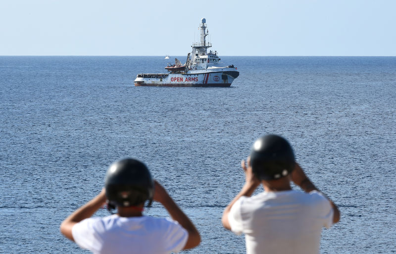 © Reuters. Turistas toman fotos del barco español de rescate de migrantes Open Arms cerca de la costa de Lampedusa en Italia.