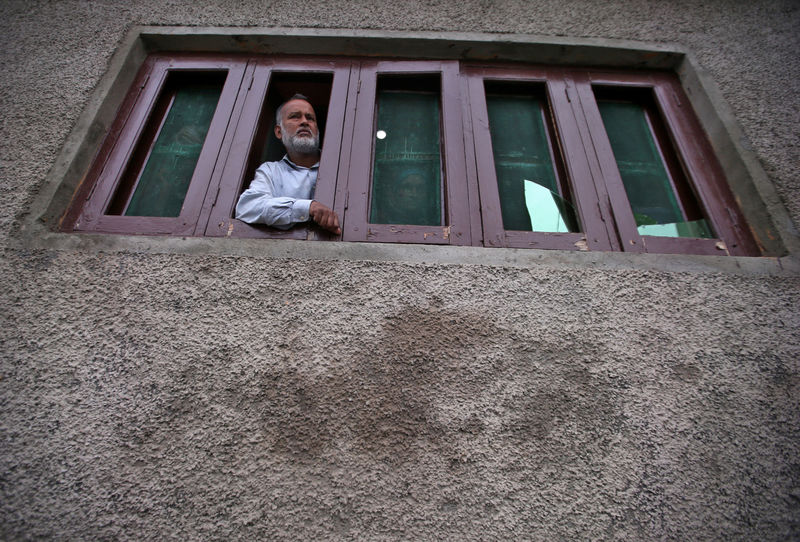 © Reuters. Kashmiri man looks out from a window of his house which was allegedly damaged by Indian security forces after clashes between protesters and the security forces on Friday evening, in Srinagar