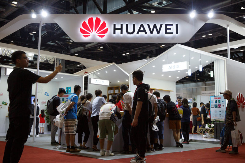 © Reuters. FILE PHOTO: People look at products at the Huawei stall at the International Consumer Electronics Expo in Beijing
