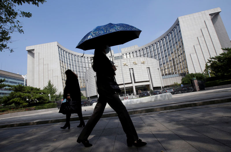 © Reuters. FILE PHOTO: People walk past the headquarters of the PBOC, the central bank, in Beijing