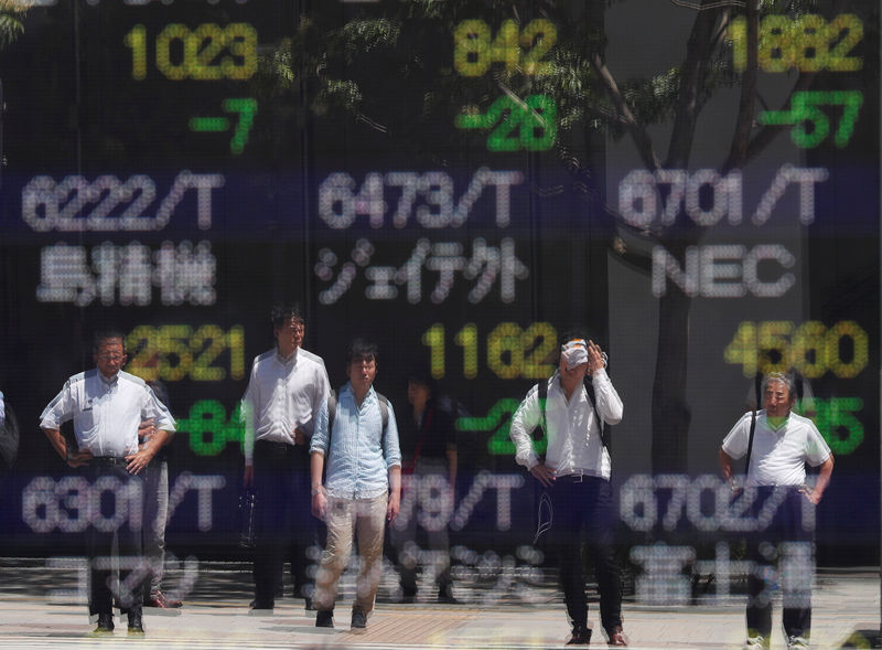 © Reuters. Passersby are reflected on a stock quotation board outside a brokerage in Tokyo