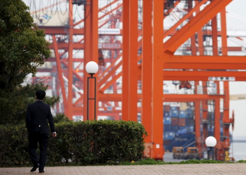 © Reuters. A businessman walks near a cargo area at a port in Tokyo