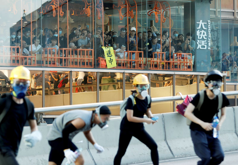 © Reuters. FILE PHOTO: People inside a restaurant watch as protesters attend a demonstration in support of the city-wide strike and to call for democratic reforms outside Central Government Complex in Hong Kong