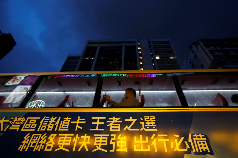 © Reuters. FILE PHOTO: A man uses a phone as he travels on a bus in Hong Kong