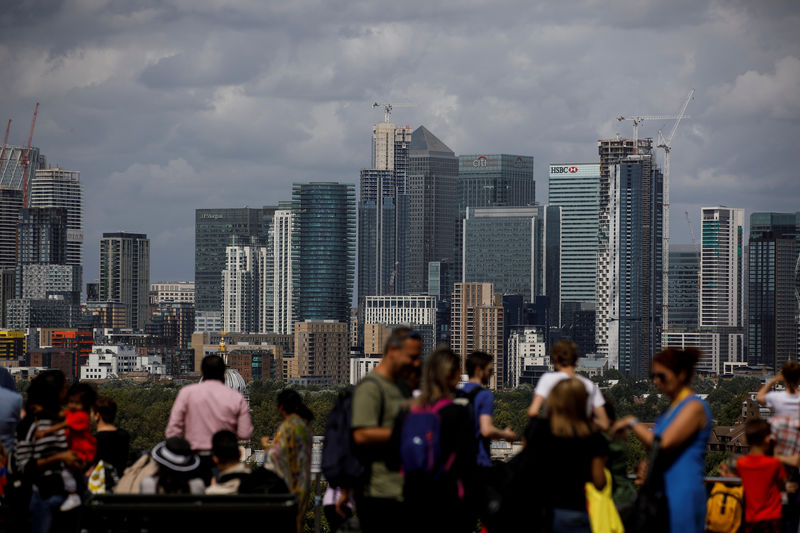 © Reuters. FILE PHOTO: People look out onto the Canary Wharf financial district as they stand at a viewing area in Greenwich Park in London