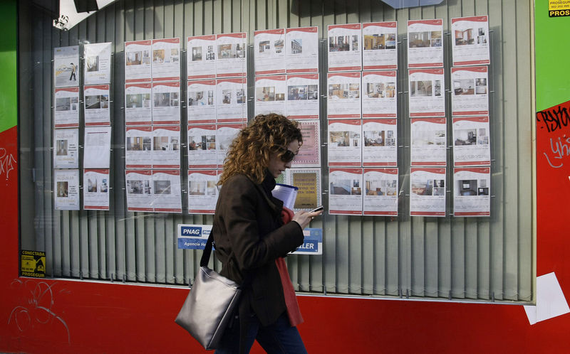 © Reuters. Una joven pasa por delante de una agencia inmobiliaria con anuncios de casas en alquiler o en venta en el centro de Madrid, el 27 de febrero de 2008