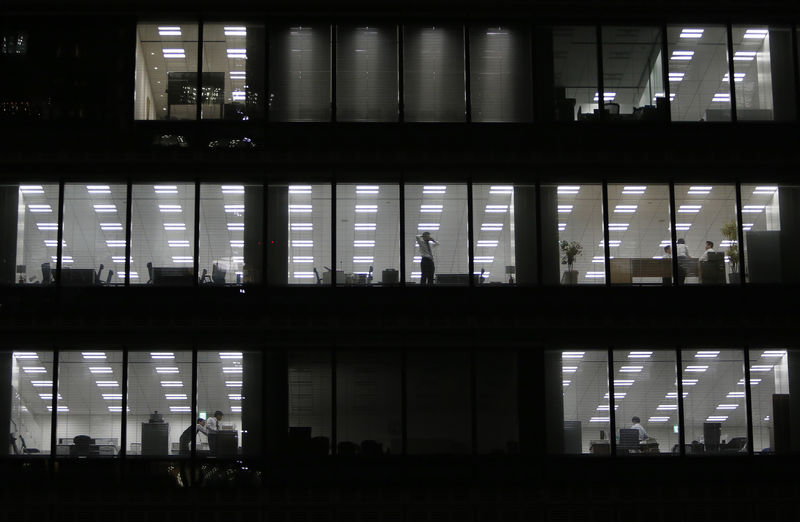 © Reuters. A man using his mobile phone stands near a glass window at a building at a Tokyo's business district
