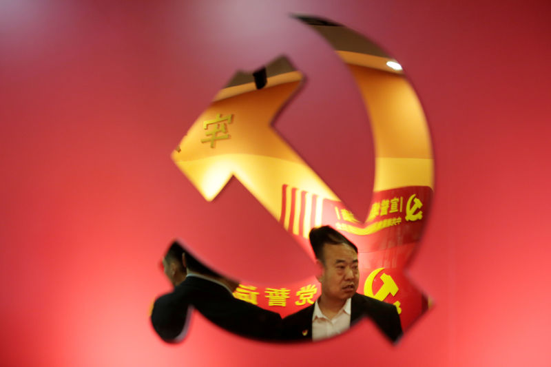 © Reuters. FILE PHOTO: Party members are reflected on a party emblem of the CPC at Tidal Star Group's party activity room in Beijing