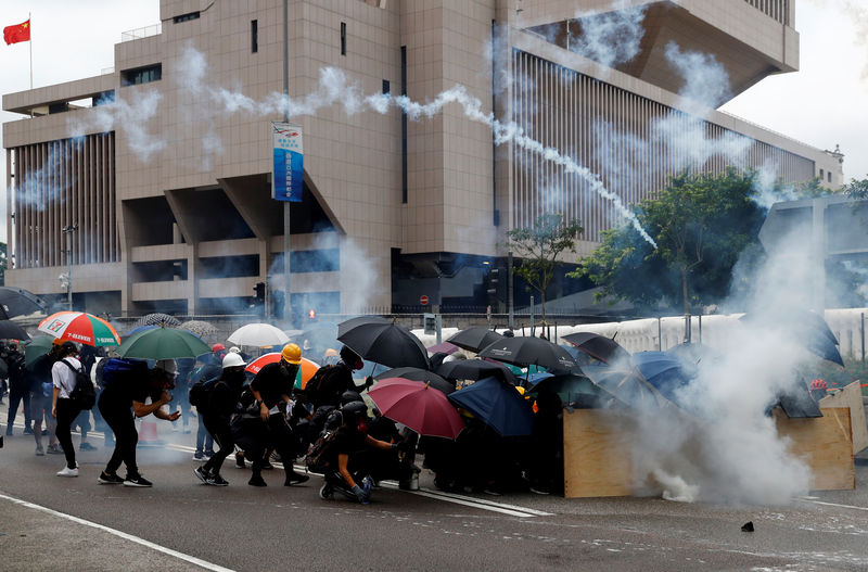 © Reuters. Demonstrators take cover as police fires tear gas during a protest in Hong Kong